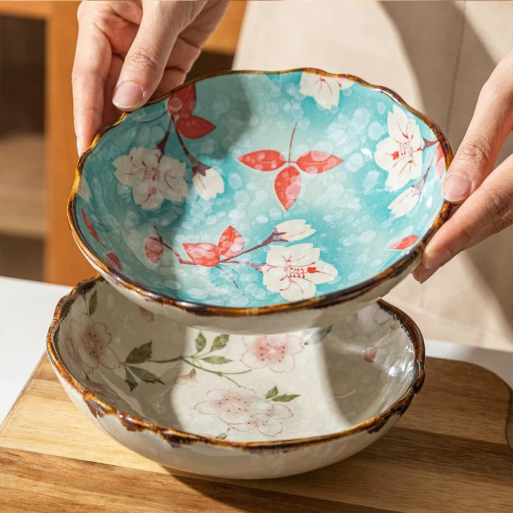 Two ceramic bowls with floral patterns held by a hand on a wooden surface.